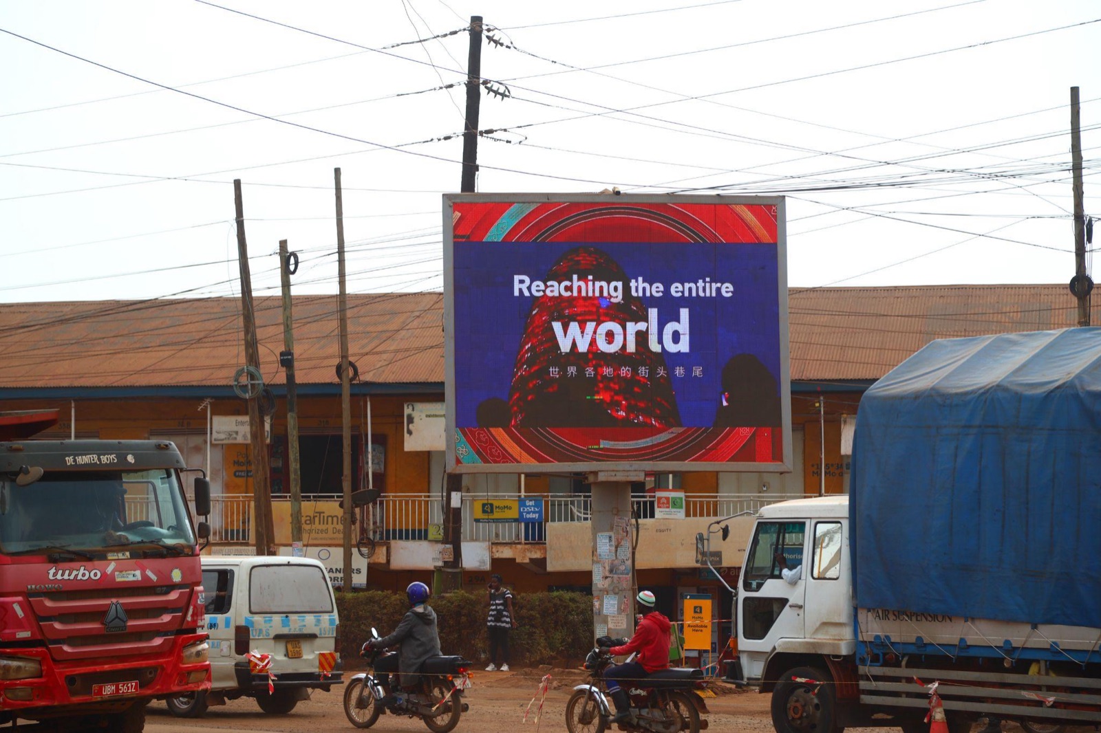 A roadside digital billboard in a busy African street running a Chinese New Year creative reading "Reaching the entire world"