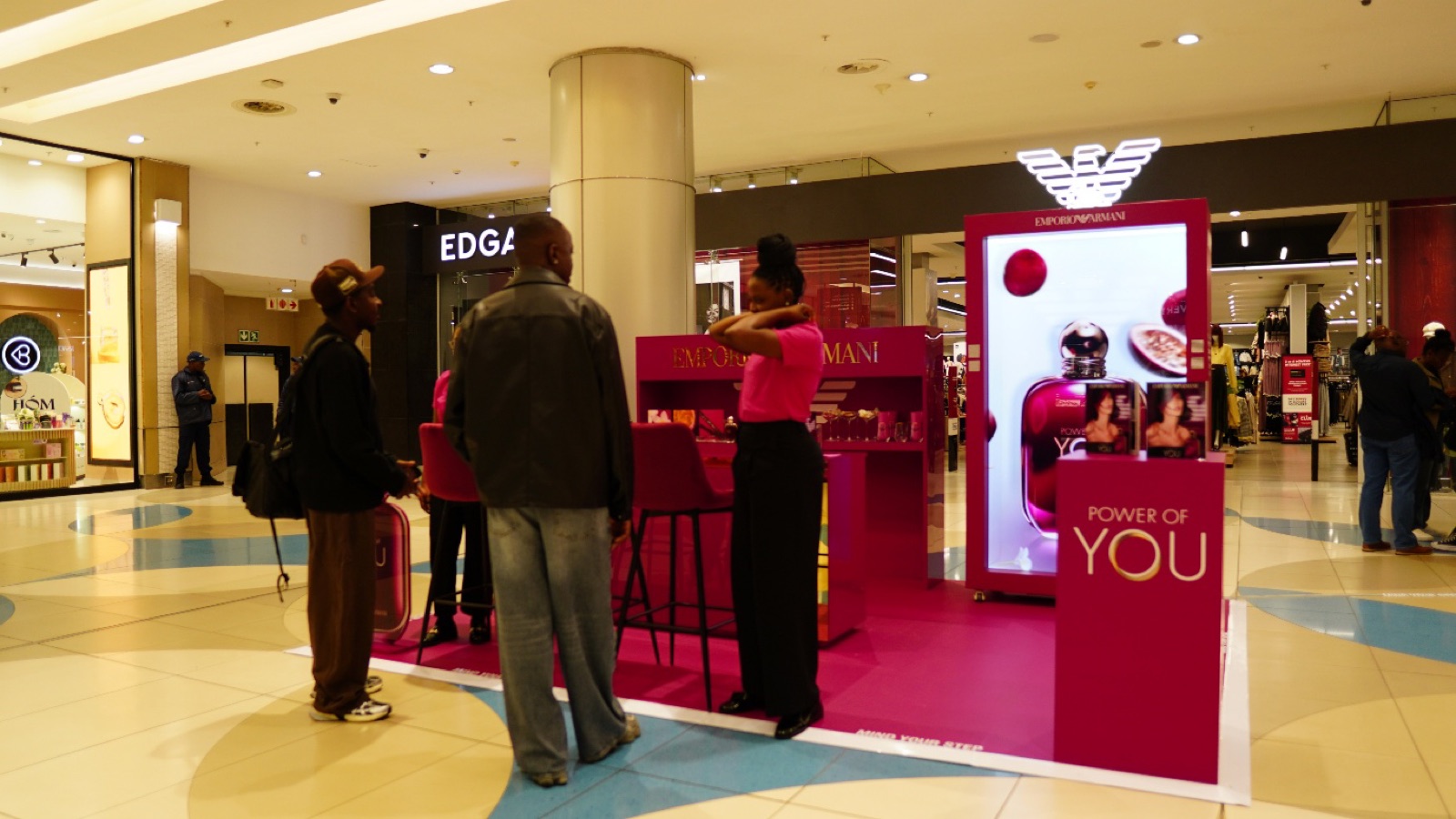 The Emporio Armani Power of You activation in a mall, with a pink counter and a Holobox hologram display of the fragrance