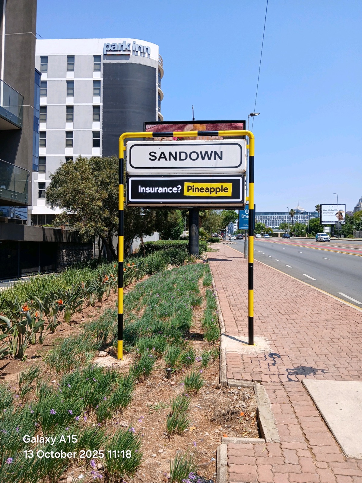 Sandown directional street sign carrying a Pineapple insurance ad