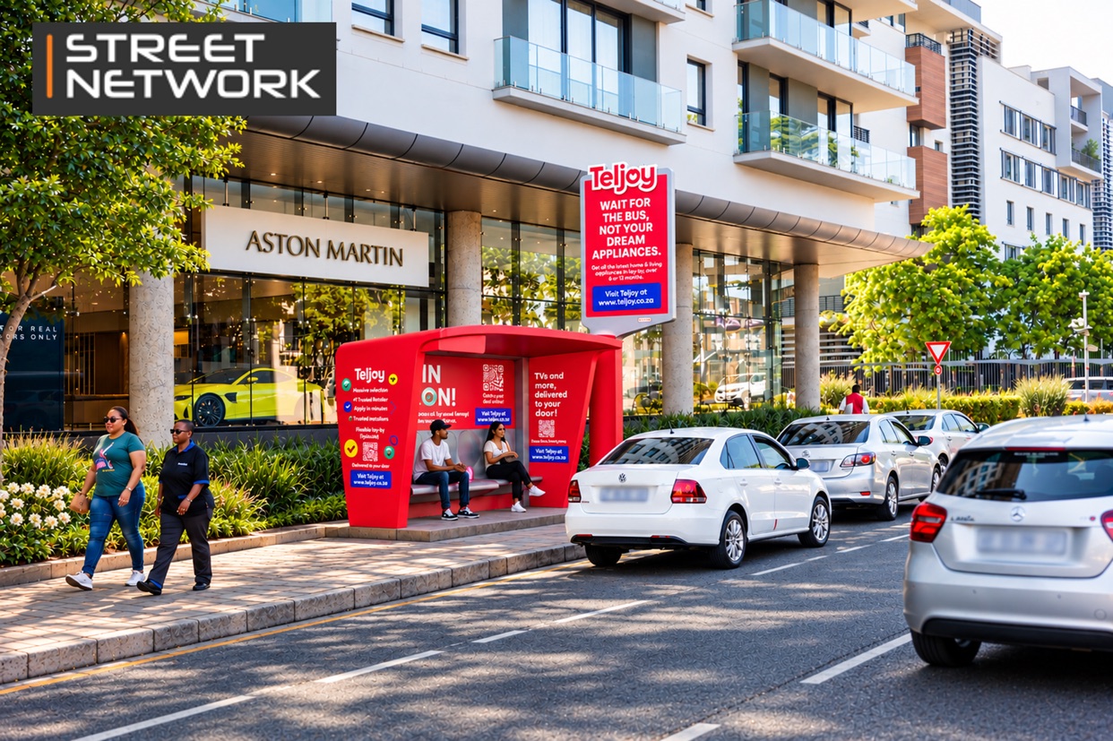 Red Teljoy-branded Street Network bus shelter on a busy city street outside an Aston Martin showroom